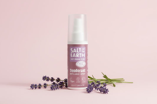 Deodorant spray bottle with lavender flowers on a pink background