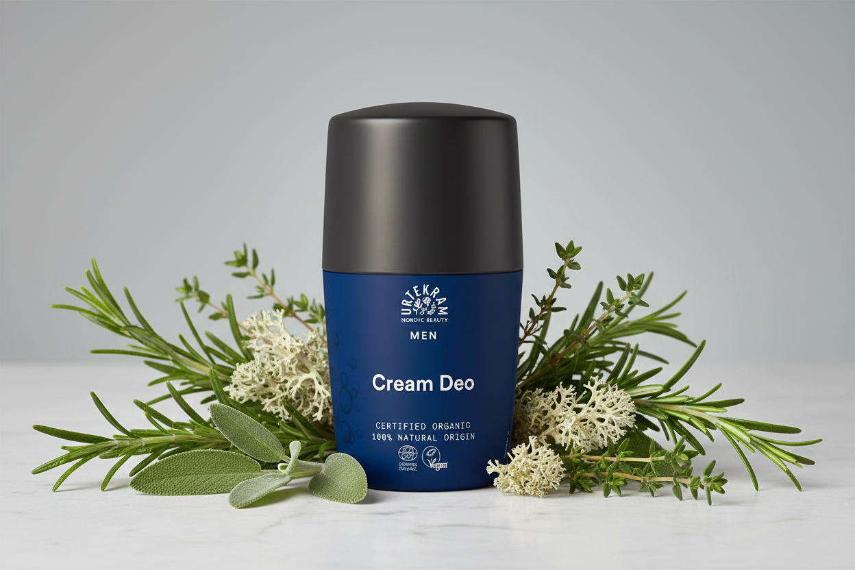 Blue deodorant stick with black cap on a white surface surrounded by green plants and flowers.