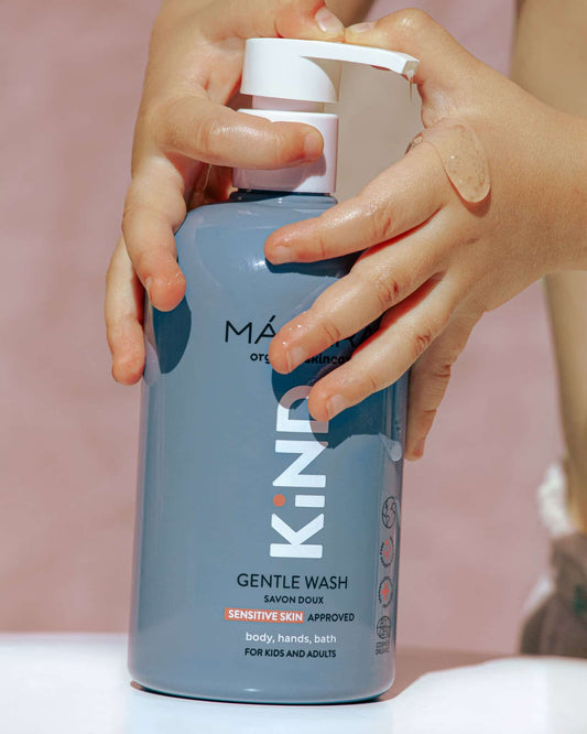 Person holding a bottle of Kind Gentle Wash with a pink background