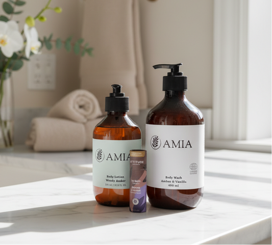 Two AMIA bottles on a bathroom counter with a mirror and flowers in the background.