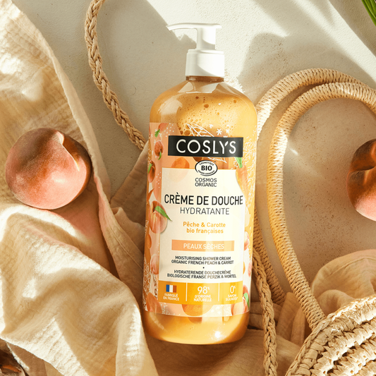 Coslys shower cream bottle with peach and carob flavor on a neutral background